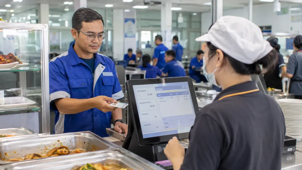 Factory employee using an employee meal subsidy system for meal redemption at a Malaysian workplace canteen